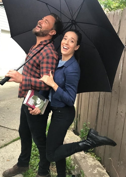 Η Μαρίνα Σκουερτσιάτι διασκεδάζει με τον συμπρωταγωνιστή της Πάτρικ Φλουέγκερ κάτω από μια ομπρέλα τον Αύγουστο του 2019