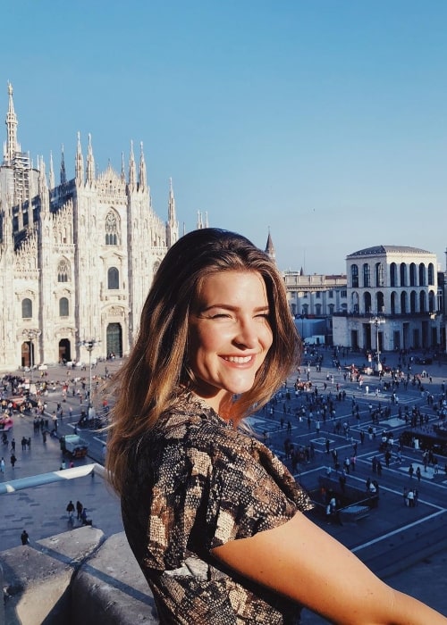 Kitty pelaa hymyillen kuvalle Milanon katedraalin taustalla syyskuussa 2019 Italiassa