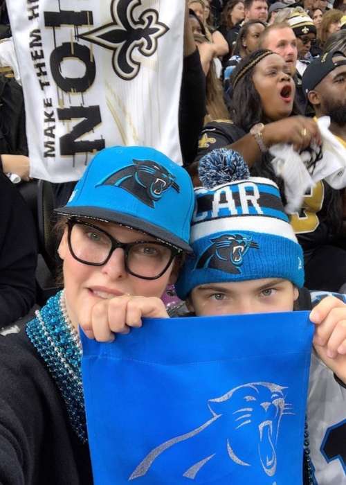 Η Linda κρατάει τη σημαία της Carolina Panthers με τον γιο της Augustin James κατά τη διάρκεια του αγώνα τους με τους New Orleans Saints τον Δεκέμβριο του 2018