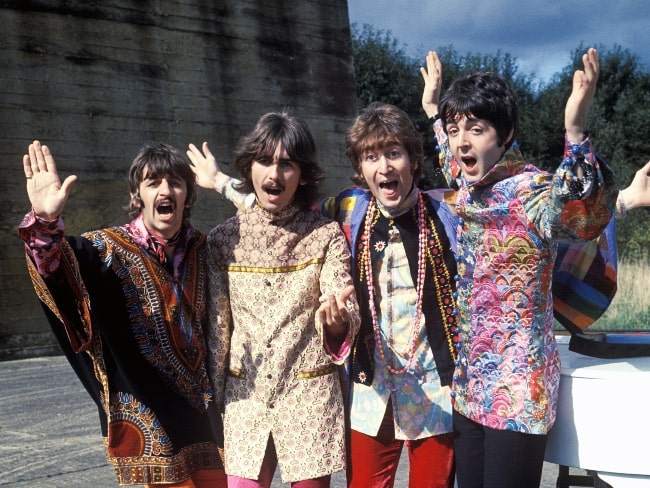 John Lennon (třetí zleva), jak je vidět na tiskové fotografii The Beatles během turné Magical Mystery Tour