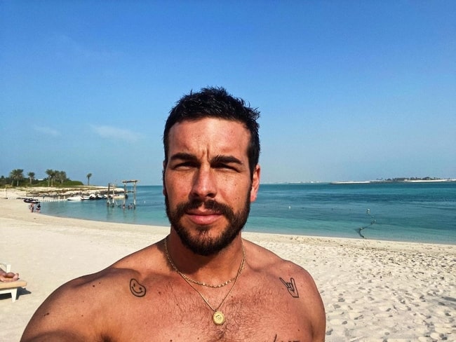 Mario Casas set, mens han tog en strandfri selfie i shirt i Abu Dhabi, De Forenede Arabiske Emirater i februar 2020