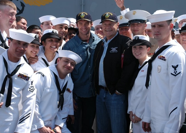 Kelsey Grammer (desno na sredini) in Hugh Jackman (na sredini levo), ki sta maja 2006 pozirala s člani posadke na letališki palubi na krovu amfibijske jurišne ladje USS Kearsarge (LHD 3).