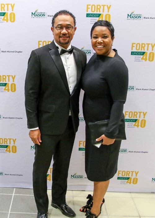 Kellie Shanygne Williams ako sa usmieva do kamery po boku svojho manžela na podujatí Black Alumni Forty Under 40 George University University v októbri 2019