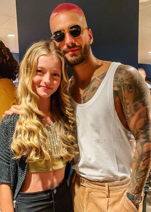Η Emily Dobson χαμογελά σε μια φωτογραφία δίπλα στον Maluma στο The Forum στο Inglewood της Καλιφόρνια τον Σεπτέμβριο του 2019